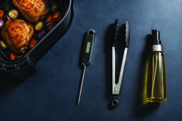 Air fryer starter kit with a digital thermometer, silicone tongs, and pump oil sprayer