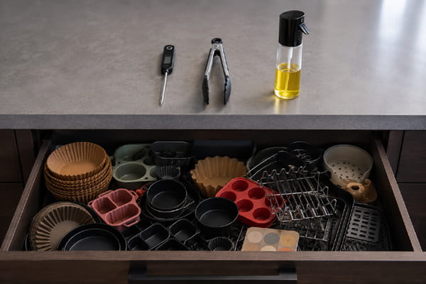 Unused air fryer accessory kits cluttering a drawer beside three practical cooking tools