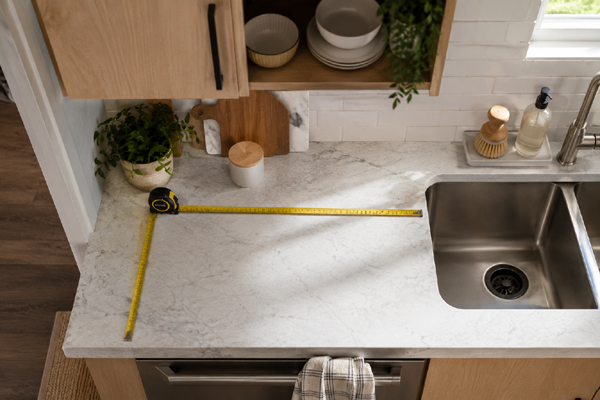 Tape measure checking counter space beside a kitchen sink for a dish rack